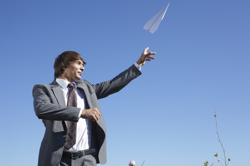 一个西装革履的外国男子在玩纸飞机图片