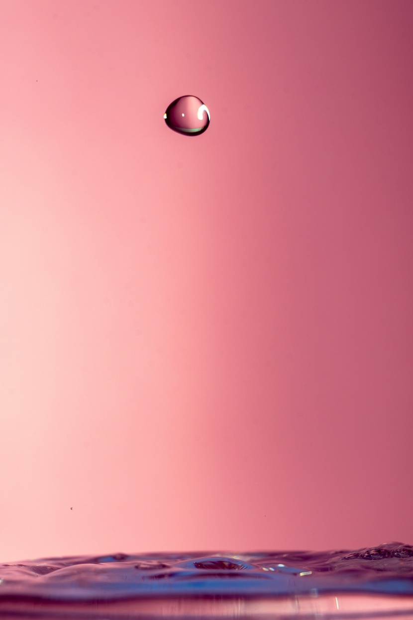 粉色背景拍摄的飞溅水滴图片