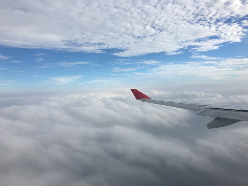 高空云層上的飛機機翼圖片